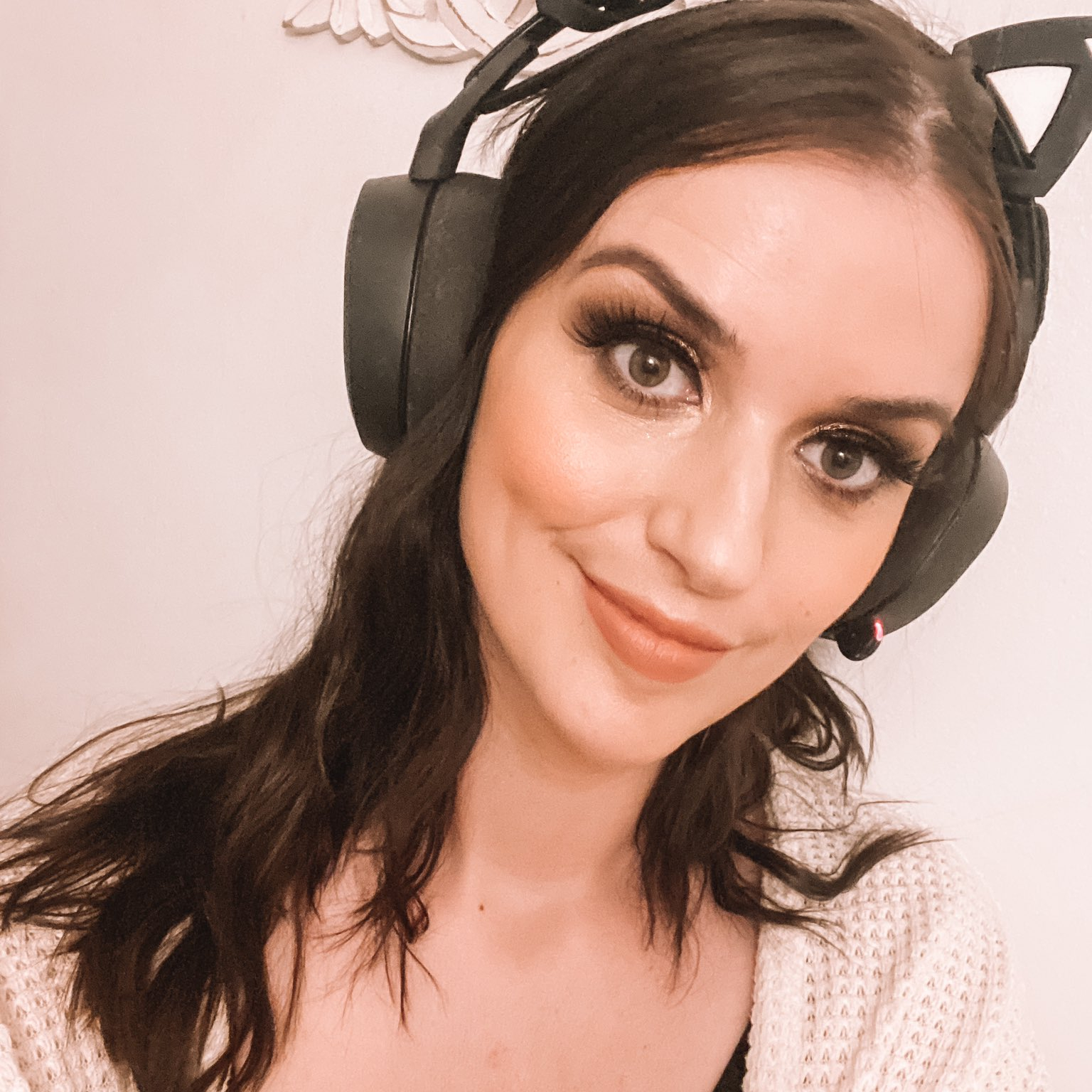 Dee smirking towards the camera while wearing a black, cat ear, headset